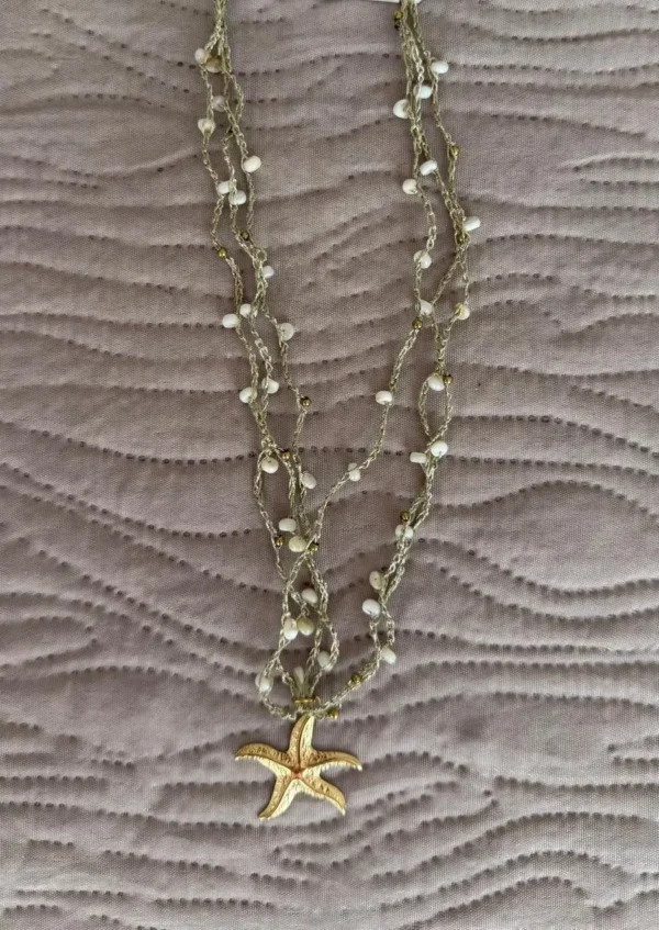 collar de estrella sobre un paño en colores dorados y verde agua