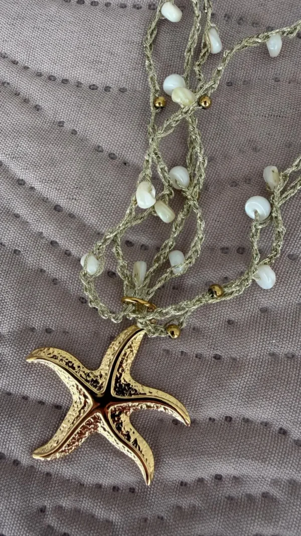 collar de estrella sobre un paño en colores dorados y verde agua